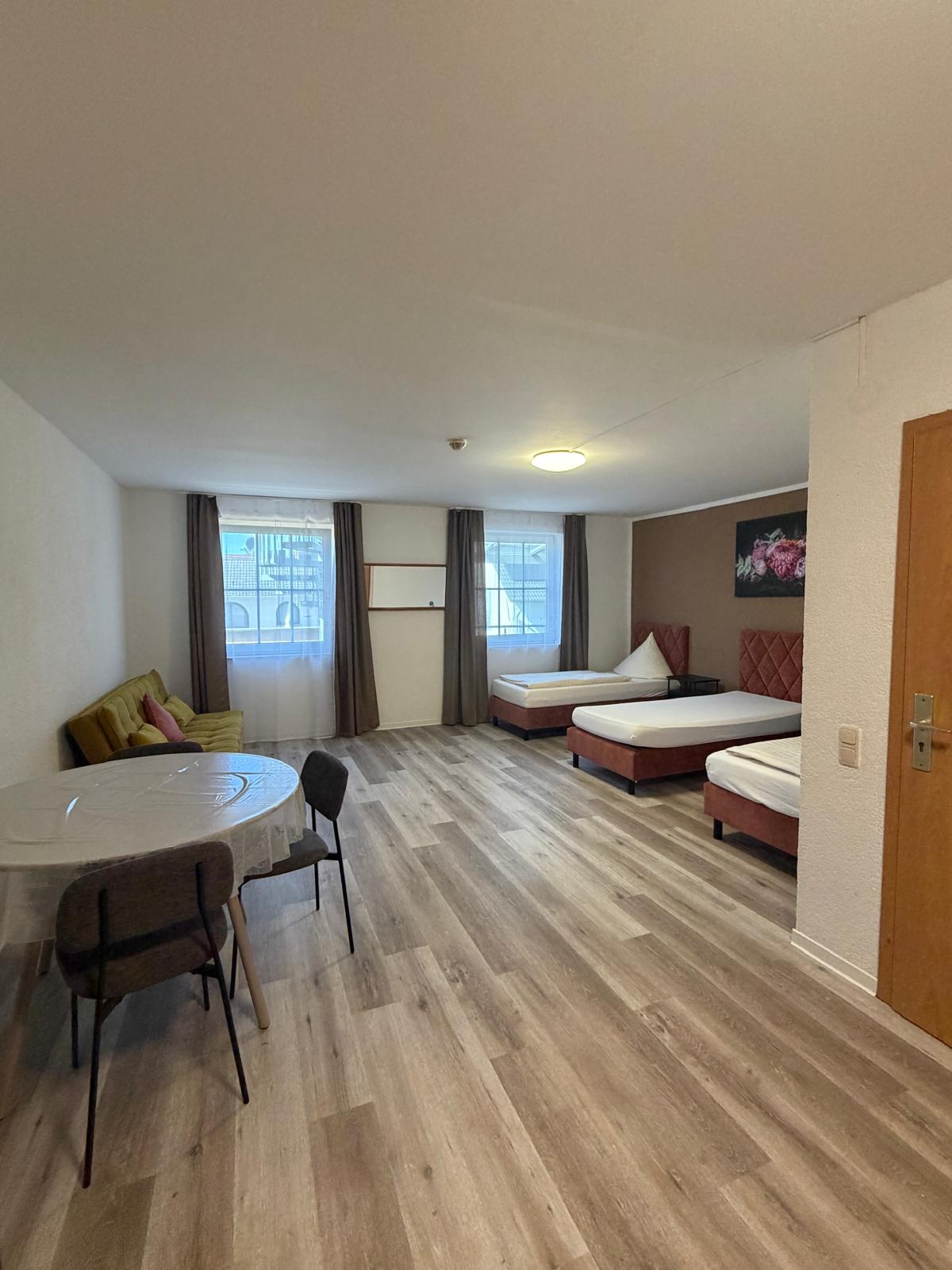 Spacious multi-bed room with sofa and dining table at Hotel Weller Riedstadt