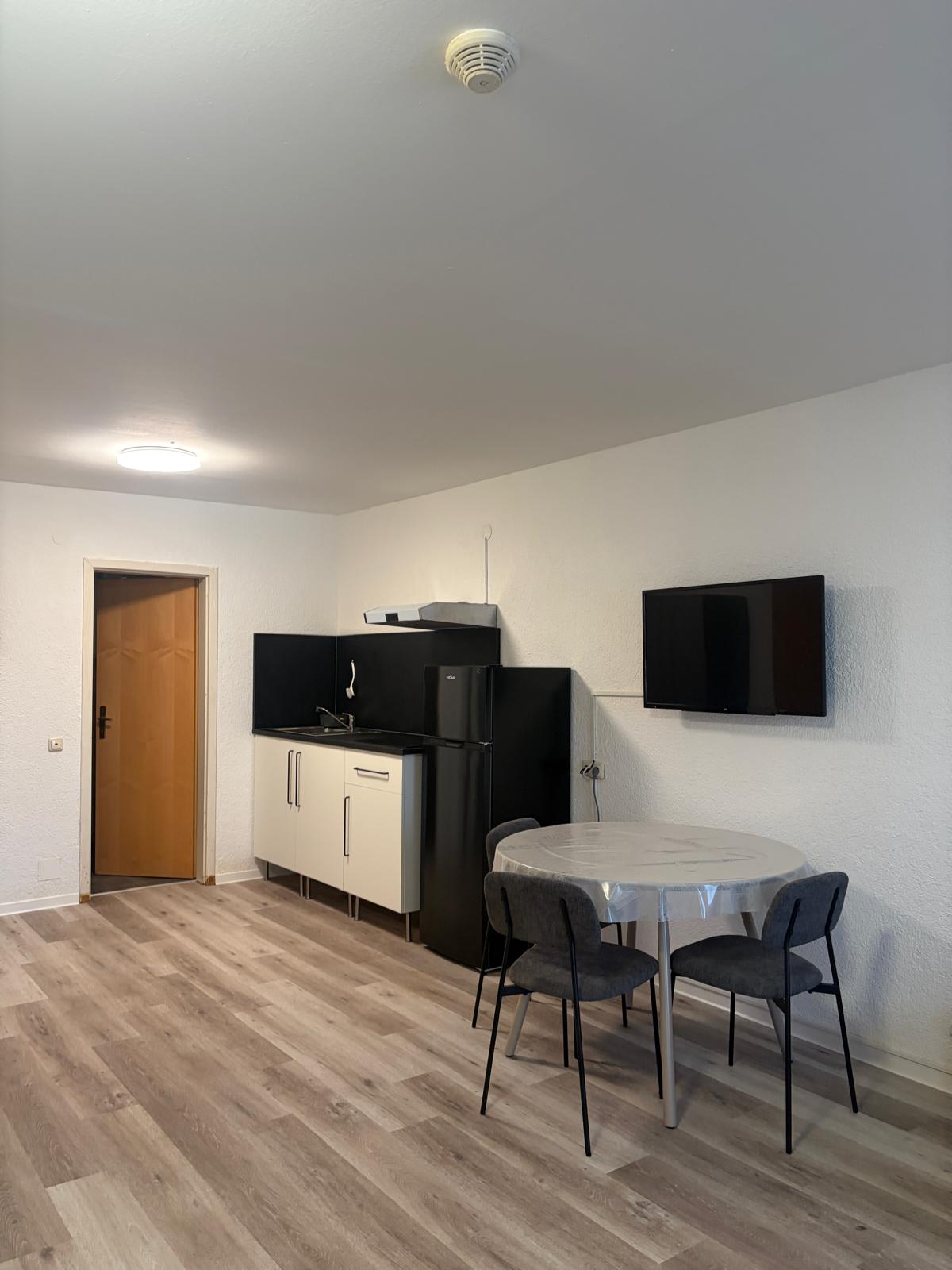 Apartment with kitchenette, black fridge and dining table at Hotel Weller Riedstadt