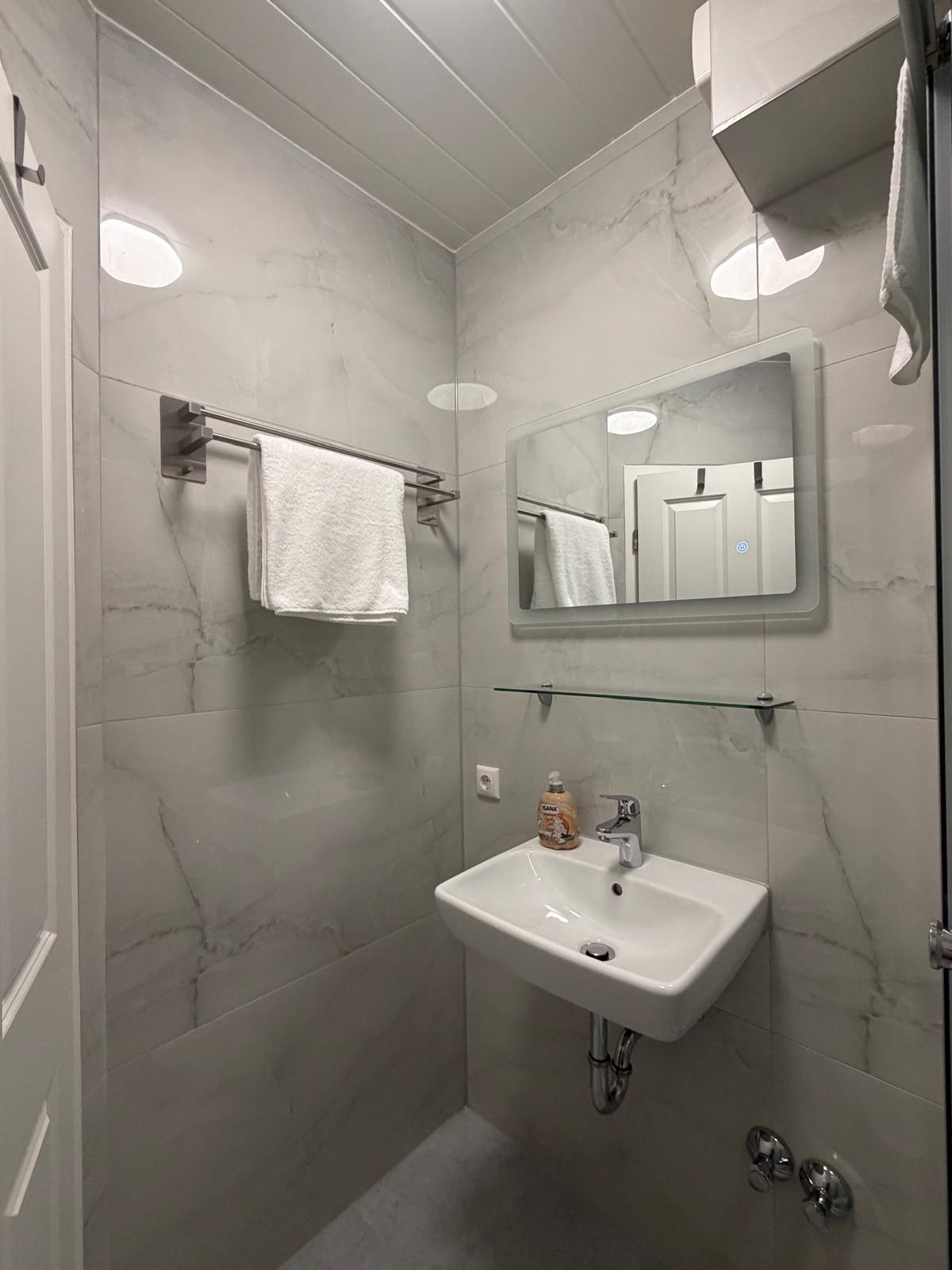 Bathroom with washbasin and LED mirror in marble look at Hotel Weller Riedstadt