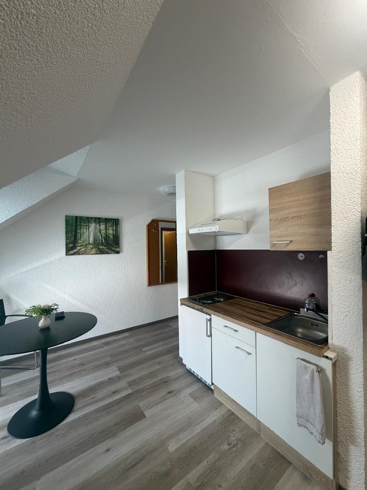 Kitchenette with round table under the sloped ceiling at Hotel Weller Riedstadt