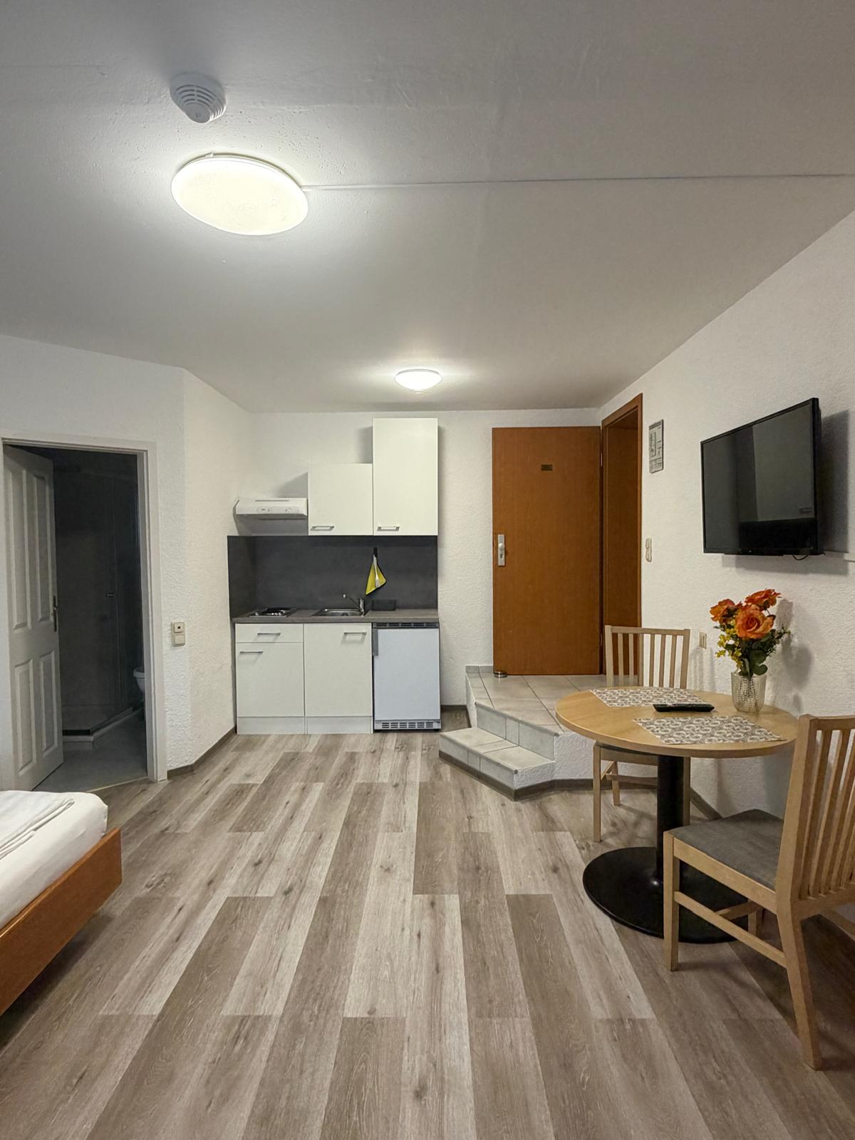 Apartment with white kitchenette and dining table at Hotel Weller Riedstadt