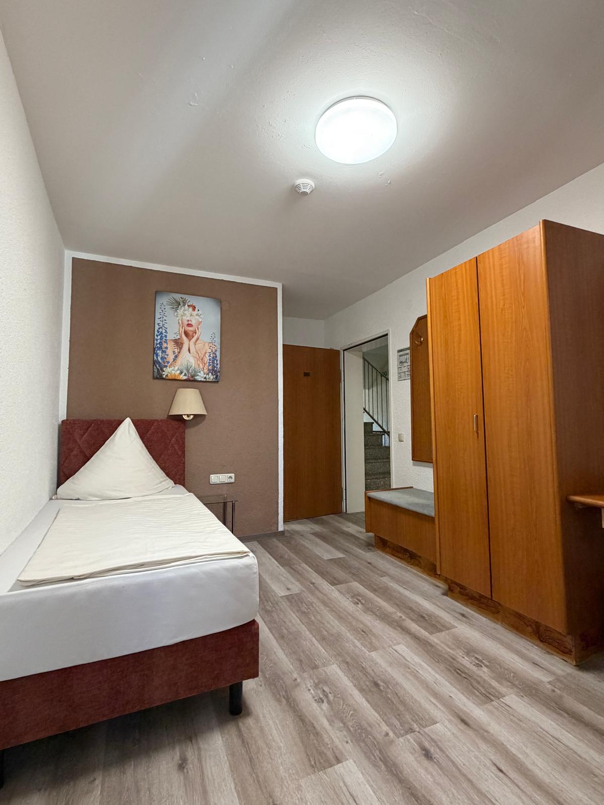 Single room with wardrobe and wall art at Hotel Weller Riedstadt