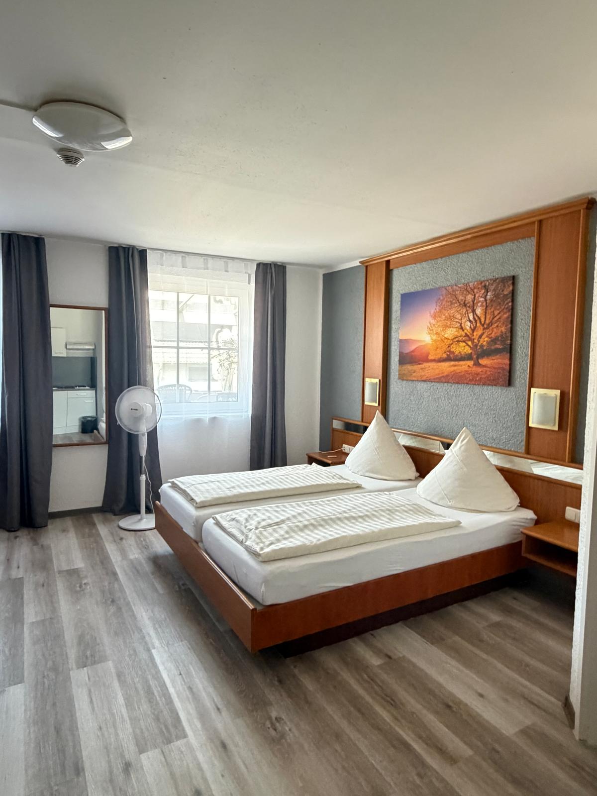 Double room with tree mural, fan and view towards the kitchenette at Hotel Weller Riedstadt