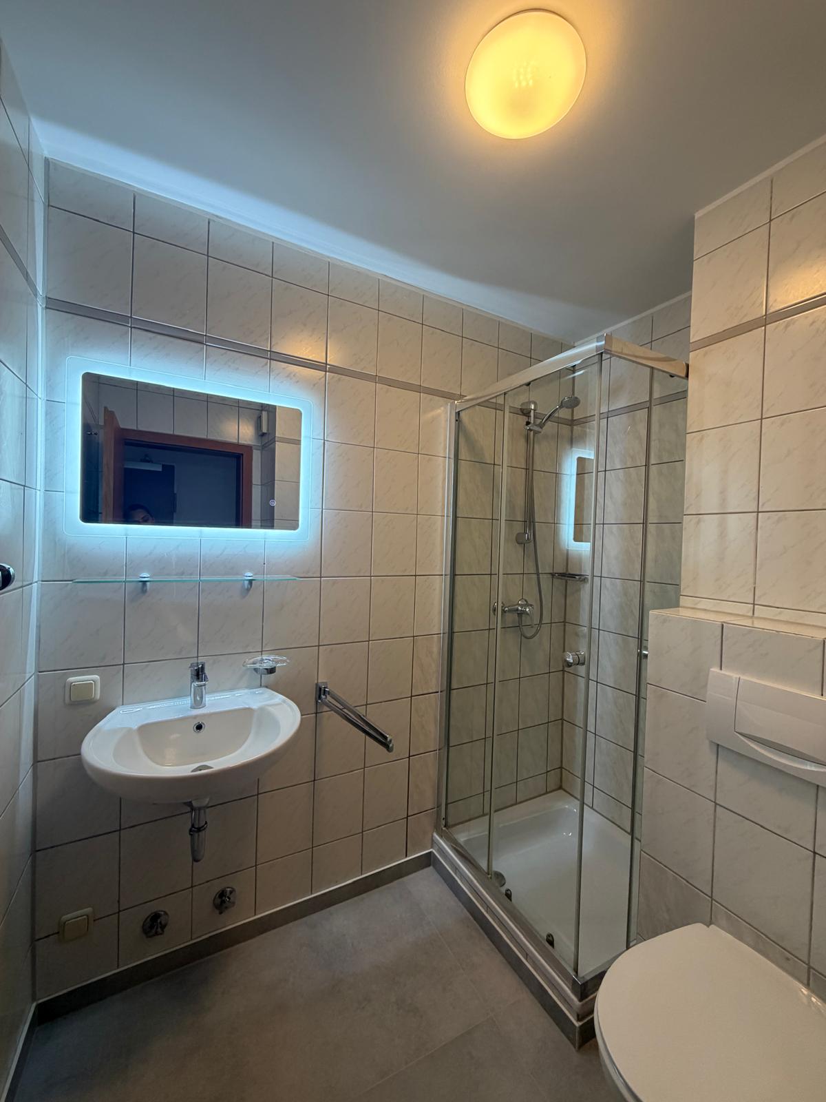 Bathroom with glass shower and illuminated mirror at Hotel Weller Riedstadt