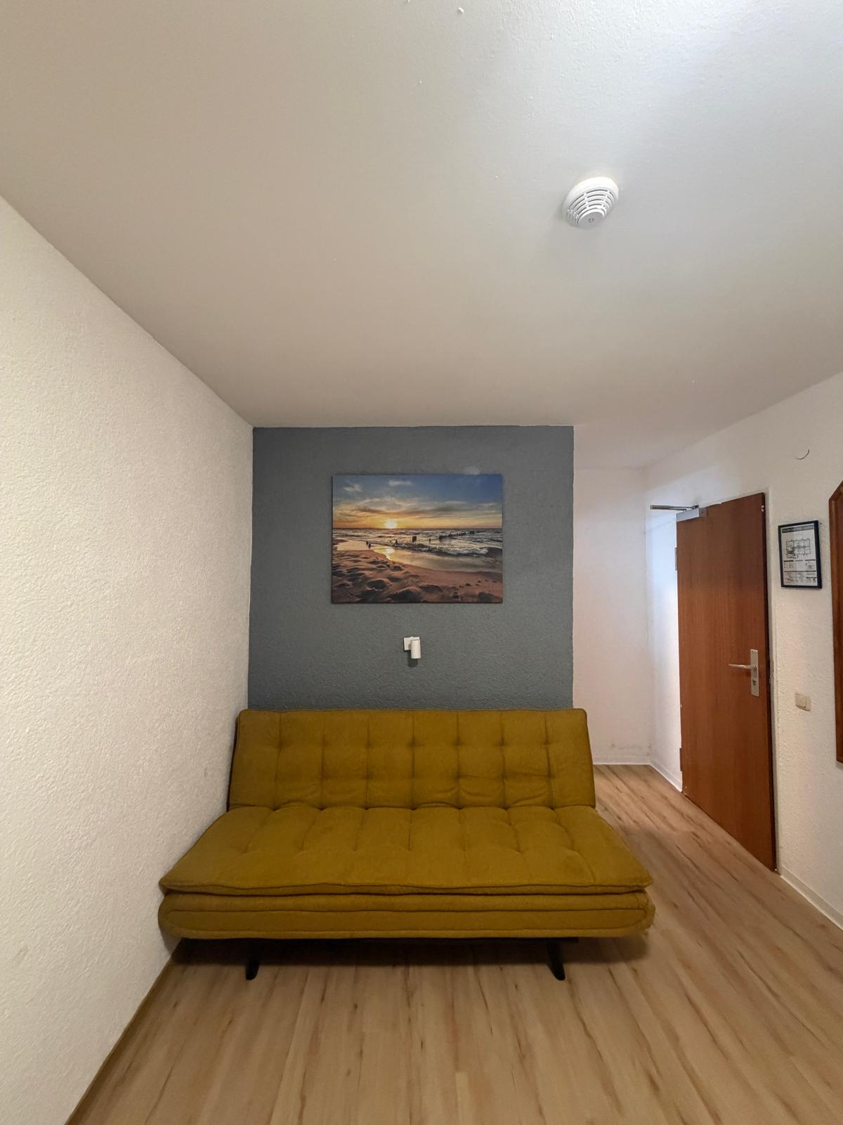 Sofa corner with beach picture in a room at Hotel Weller Riedstadt