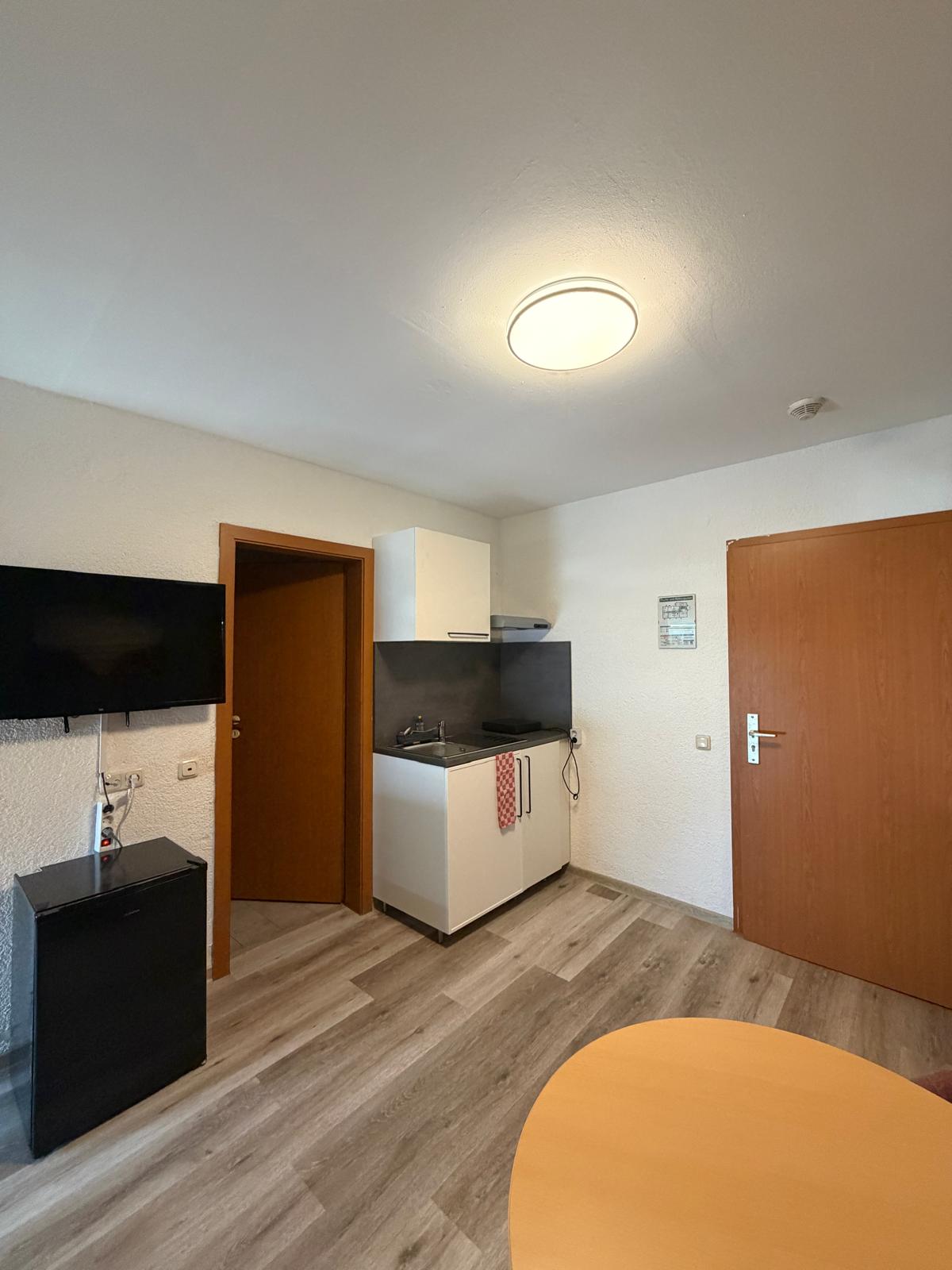 Kitchenette with fridge and TV in the contractor room at Hotel Weller Riedstadt
