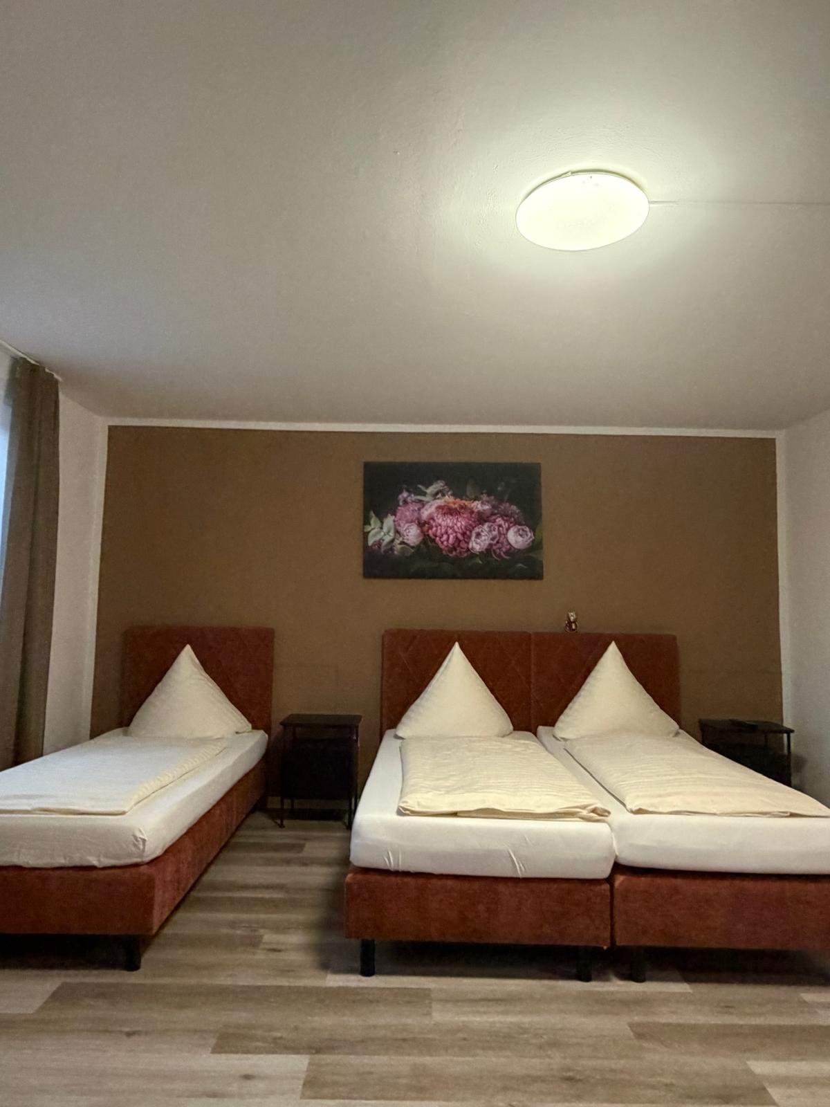 Triple room with double bed, single bed and floral picture at Hotel Weller Riedstadt
