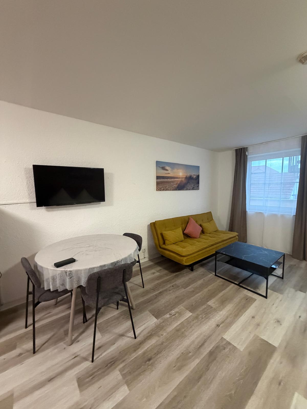 Living area with yellow sofa, coffee table and TV at Hotel Weller Riedstadt