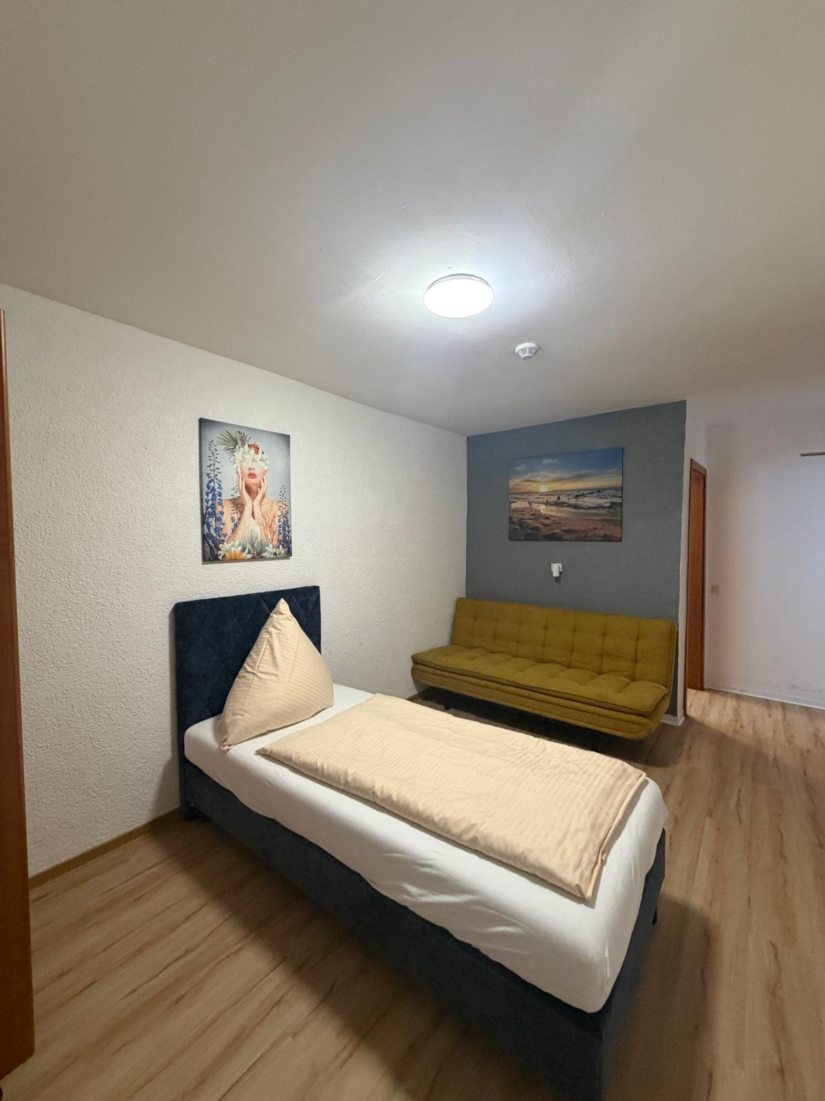 Single room with yellow sofa and wall art at Hotel Weller Riedstadt