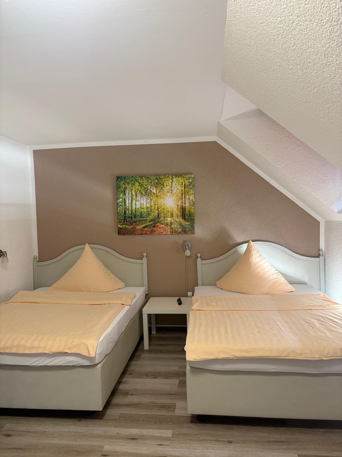 Twin room under the sloped ceiling with two single beds and forest picture at Hotel Weller Riedstadt