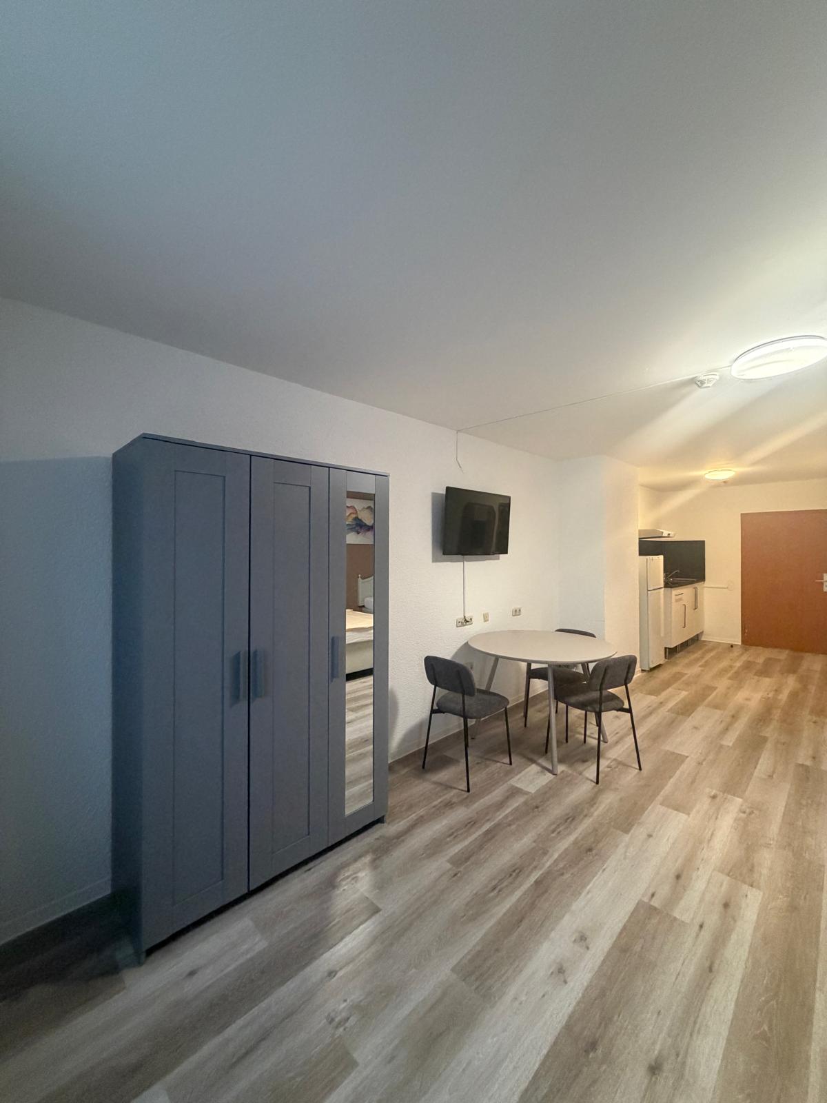 Room with mirrored wardrobe, dining table and TV at Hotel Weller Riedstadt