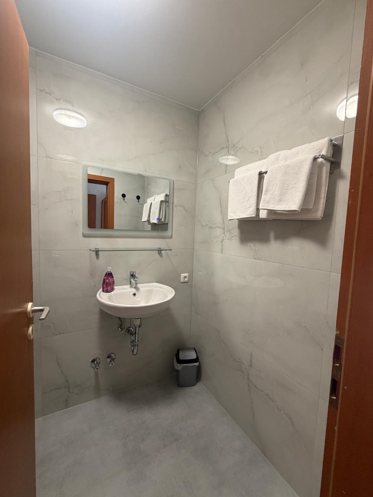 Bathroom in marble look with washbasin, mirror and towels at Hotel Weller Riedstadt